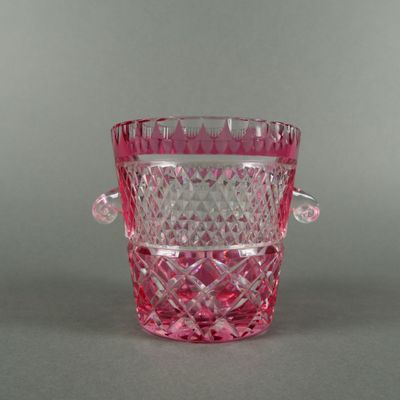un vase en verre rose muni d'une anse, posé sur une table