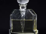 an image of a glass perfume bottle with a flower on it
