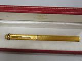 an image of a gold pen in a red box on a white surface