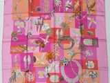 un gros plan d'un foulard carré rose et orange posé sur une table
