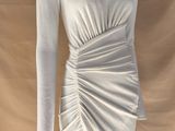 Le mannequin porte une robe blanche à manches longues.