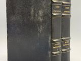 un vieux livre noir sur lequel sont posés trois livres