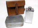 a silver flask and a leather case on a white surface