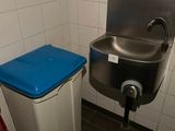 un lavabo et une poubelle dans des toilettes publiques