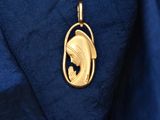 a close up of a gold fish pendant on a blue shirt