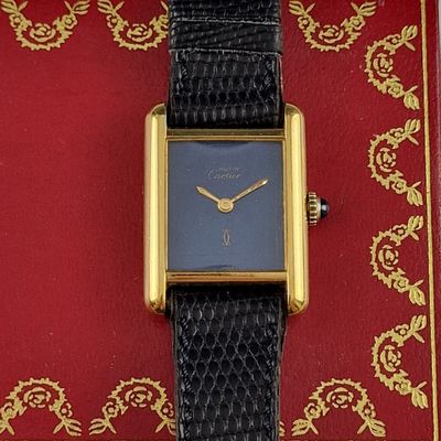 a gold and black watch on a red and gold book