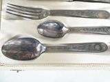 five silver spoons and two silver forks in a box