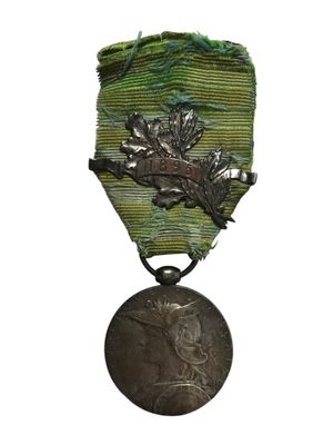 une vieille médaille en argent, suspendue à un ruban vert