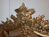 a mirror with a gold frame and a gold bird on it