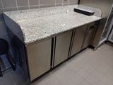a counter with a sink and a refrigerator in the kitchen