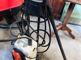 une machine rouge et noire posée par terre à côté d'une table