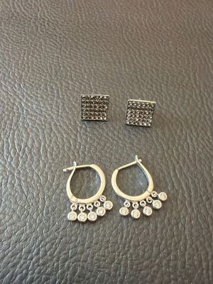 a pair of earrings and a pair of earrings on a leather surface