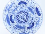 a blue and white plate with fish and flowers on it