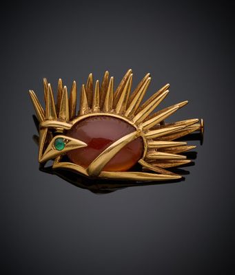 une broche en or ornée d'une pierre rouge entourée de pointes