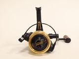 a black and gold fishing reel on a white surface