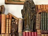 a statue of a woman sitting on top of a pile of books