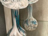 two glass vases that are sitting on a glass shelf