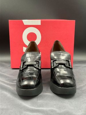 une paire de chaussures noires posée sur une boîte rouge
