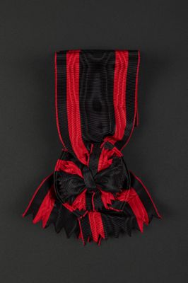 a red and black ribbon with a black bow on a black background