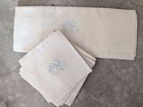 trois serviettes blanches ornées de monogrammes bleus et d'un monogramme