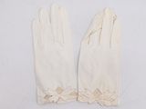 two pairs of white gloves with bows on them on a white surface