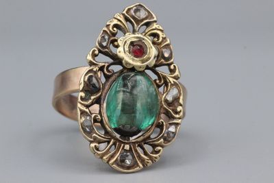 Gros plan sur une bague en or ornée d'une pierre verte