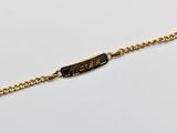 a close up of a gold chain bracelet with a black tag on it