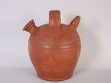 a brown vase with three handles on a white surface