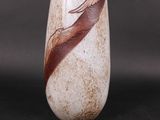 a white vase with a brown feather on it