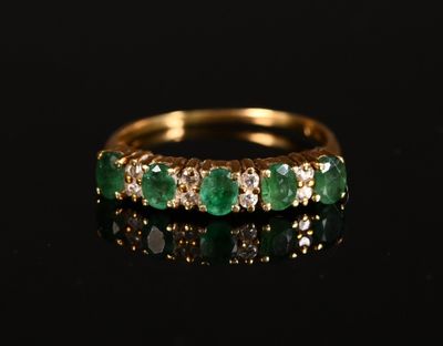 une bague en or sertie d'émeraudes et de diamants sur un fond noir