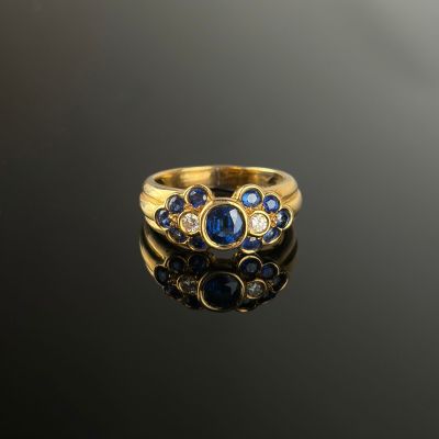 a close up of a gold ring with blue sapphires and diamonds