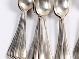 six silver spoons are lined up in a row on a white surface