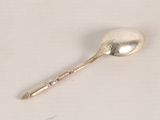 a silver spoon with a spoon handle on a white surface