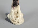 figurine of a woman in a white robe sitting on a gray surface