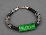 un bracelet composé d'une perle en verre verte montée sur un cordon en cuir noir