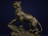 a bronze statue of a tiger on a rock