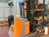 a forklift in a warehouse with pallets of wood in the background