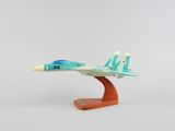 une petite maquette d'avion de chasse posée sur un socle en bois