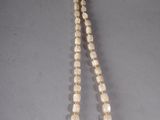 a close up of a necklace on a table with a white background
