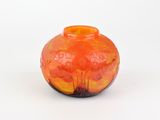 un vase orange posé sur une surface blanche