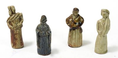 quatre figurines en céramique représentant des personnes alignées sur une surface blanche