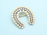 a close up of a brooch with pearls on a blue background