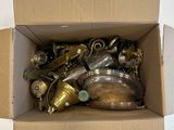 a cardboard box full of brass items on a white surface