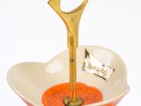 a white and orange plate with a gold spoon in it