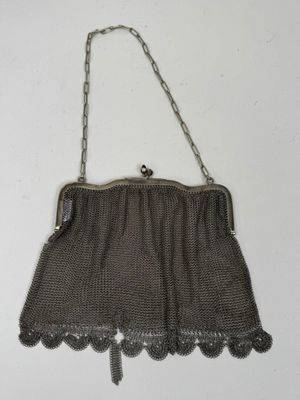 un vieux sac à main en maille argentée, muni d'une poignée et d'une bandoulière en chaîne