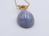a necklace with a blue stone and gold chain on a white surface