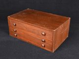 an old wooden box with three drawers sitting on a black surface