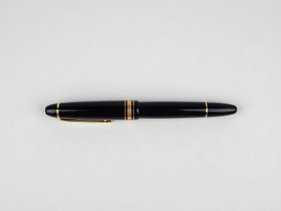 un stylo plume noir et doré posé sur une surface blanche