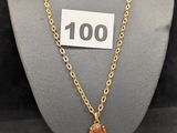 une photo d'un collier porté par un mannequin, sur lequel figure le chiffre 100