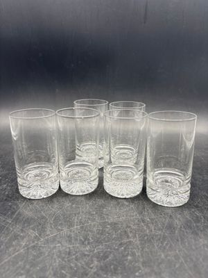 six verres à shot alignés sur une table, sur fond noir